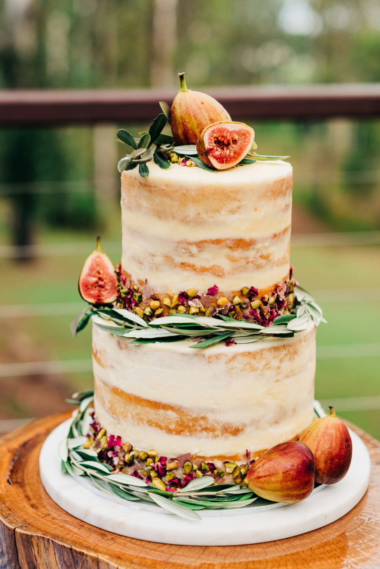 A wedding cake with greenery and fruit.